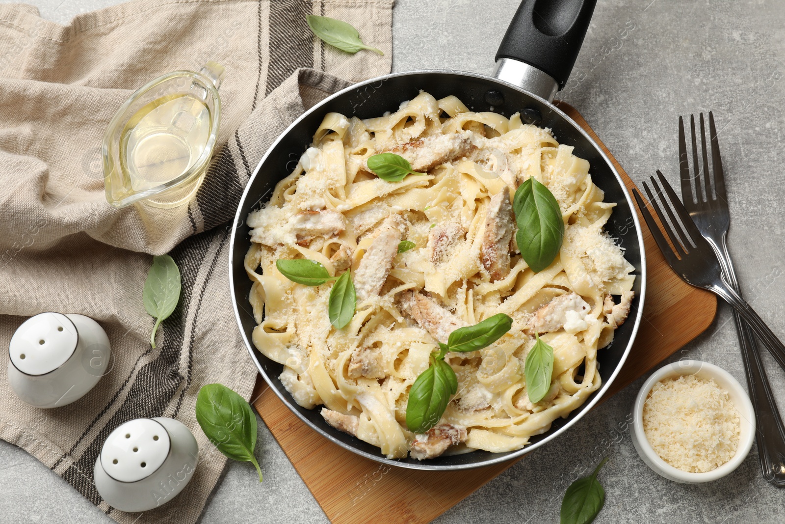 Photo of Delicious pasta Alfredo with chicken served on grey table, flat lay