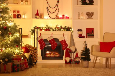 Photo of Stylish fireplace, Christmas tree with festive decor and presents indoors