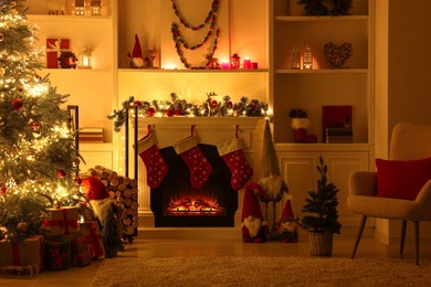 Photo of Stylish fireplace, Christmas tree with festive decor and presents indoors