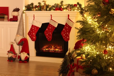 Photo of Stylish fireplace, Christmas tree with festive decor and presents indoors