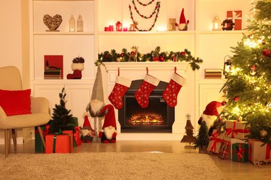 Photo of Stylish fireplace, Christmas tree with festive decor and presents indoors