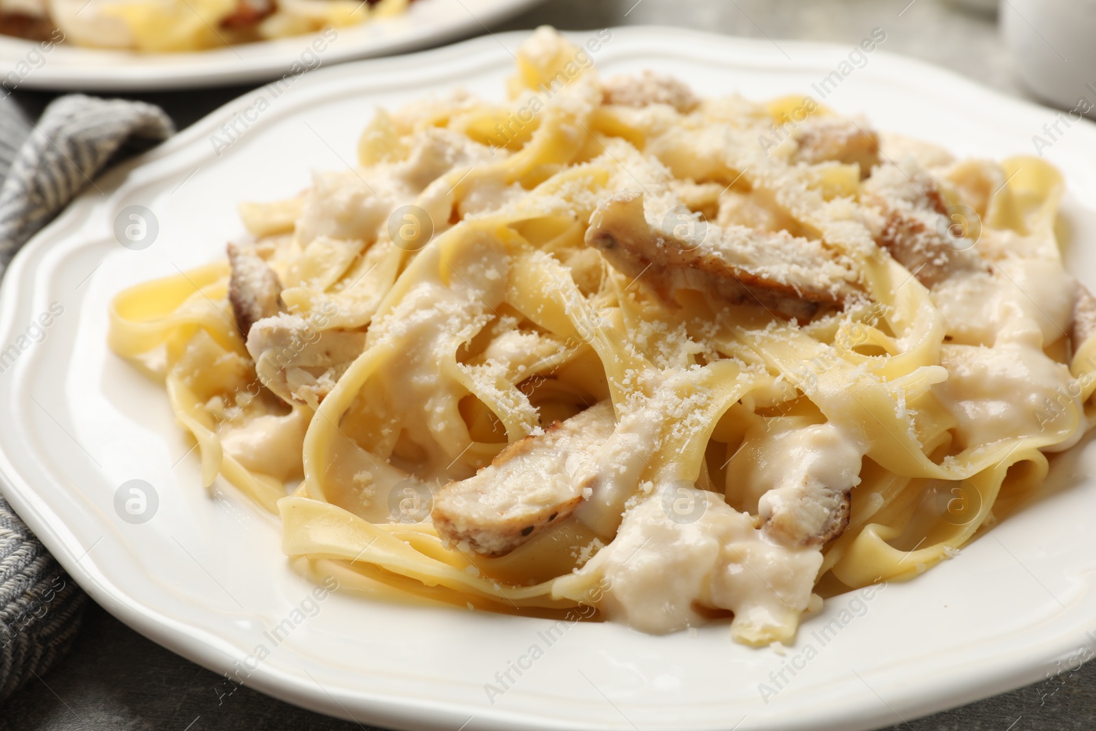 Photo of Tasty Alfredo pasta with chicken on table, closeup