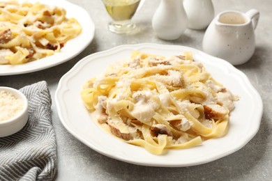 Photo of Tasty Alfredo pasta with chicken on gray textured table, closeup