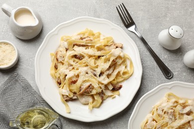 Photo of Tasty Alfredo pasta with chicken served on gray textured table, flat lay