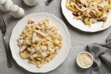 Photo of Tasty Alfredo pasta with chicken served on gray textured table, flat lay