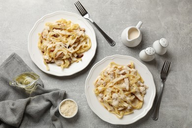 Photo of Tasty Alfredo pasta with chicken served on gray textured table, flat lay