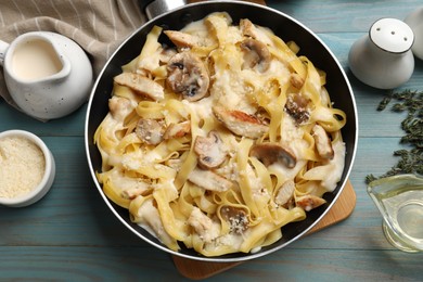 Photo of Flat lay composition with tasty Alfredo pasta with chicken and mushrooms on light blue wooden table