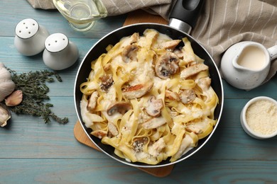 Photo of Flat lay composition with tasty Alfredo pasta with chicken and mushrooms on light blue wooden table