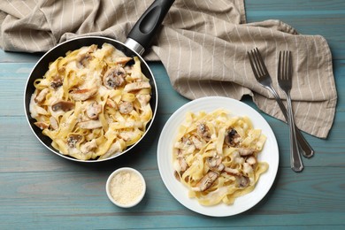 Photo of Tasty Alfredo pasta with chicken served on light blue wooden table, flat lay