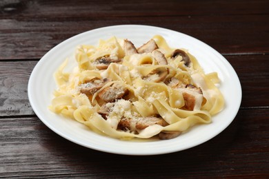 Photo of Tasty Alfredo pasta with chicken and mushrooms on wooden table, closeup