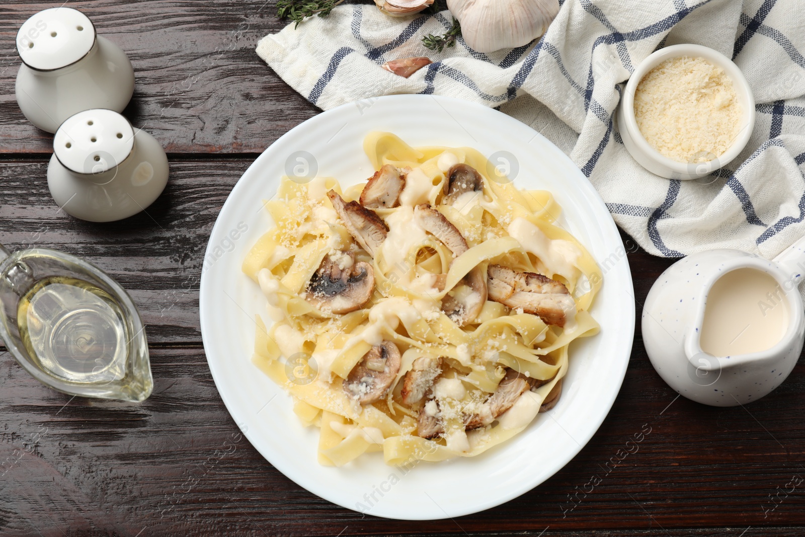 Photo of Tasty Alfredo pasta with chicken, mushrooms, cheese and creamy sauce on wooden table, flat lay