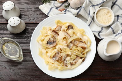 Photo of Tasty Alfredo pasta with chicken, mushrooms, cheese and creamy sauce on wooden table, flat lay