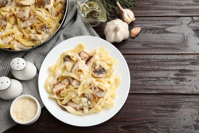 Photo of Flat lay composition with tasty Alfredo pasta with chicken and mushrooms on wooden table, space for text