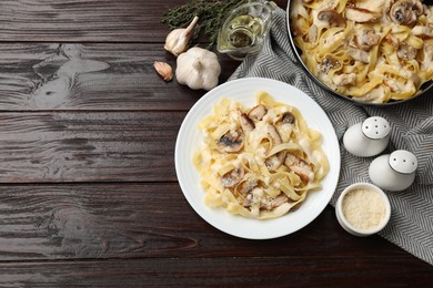 Photo of Flat lay composition with tasty Alfredo pasta with chicken and mushrooms on wooden table, space for text