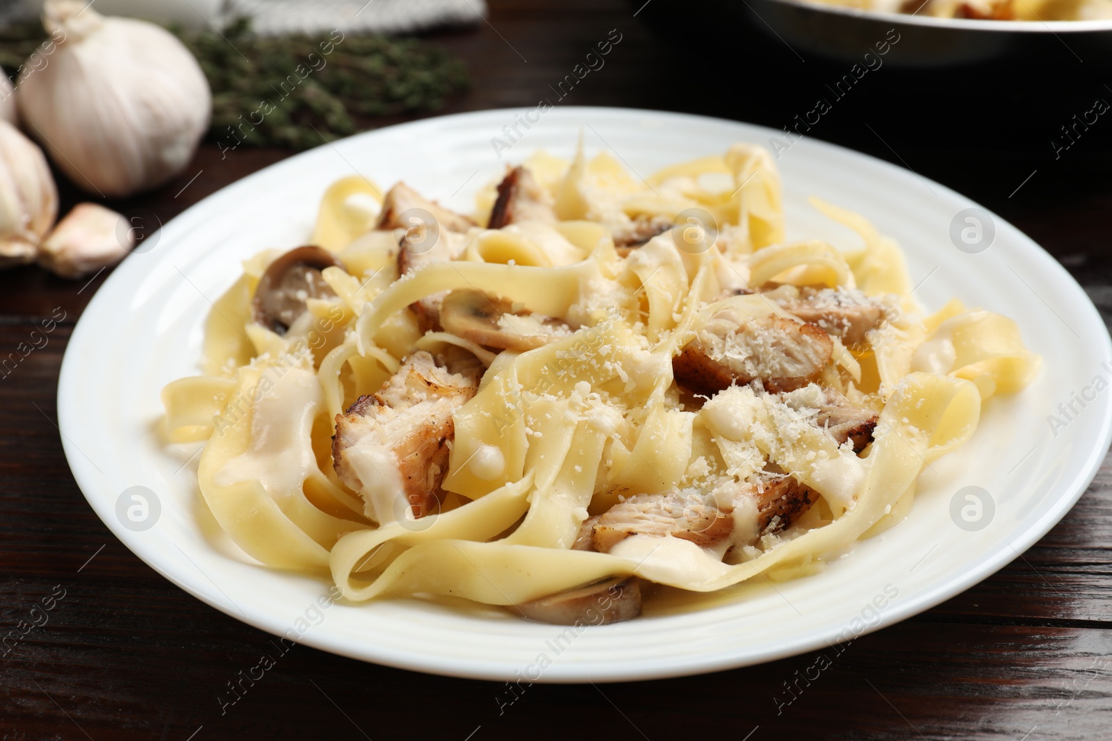 Photo of Tasty Alfredo pasta with chicken and mushrooms on wooden table, closeup