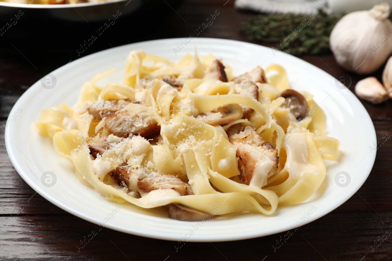 Photo of Tasty Alfredo pasta with chicken and mushrooms on wooden table, closeup