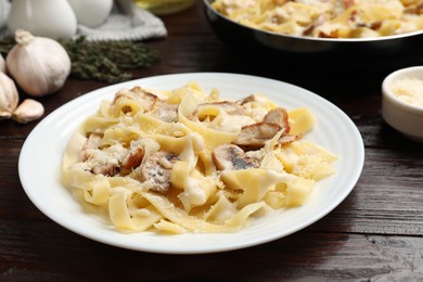 Photo of Tasty Alfredo pasta with chicken and mushrooms on wooden table, closeup