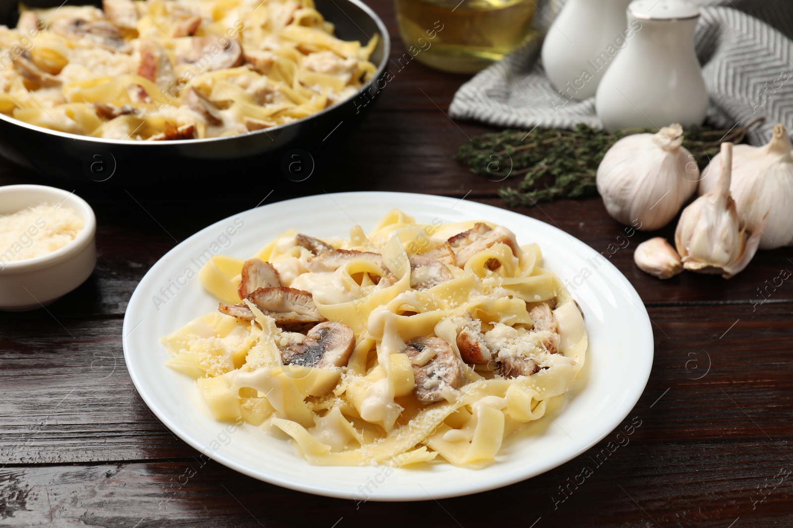 Photo of Tasty Alfredo pasta with chicken and mushrooms on wooden table, closeup