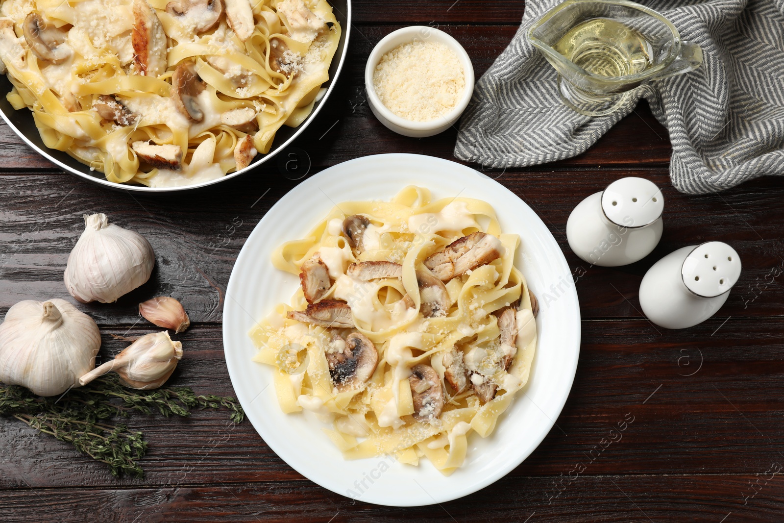 Photo of Flat lay composition with tasty Alfredo pasta with chicken and mushrooms on wooden table