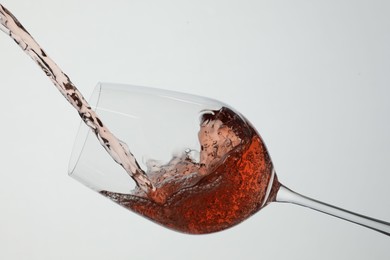 Photo of Pouring rose wine into glass on white background