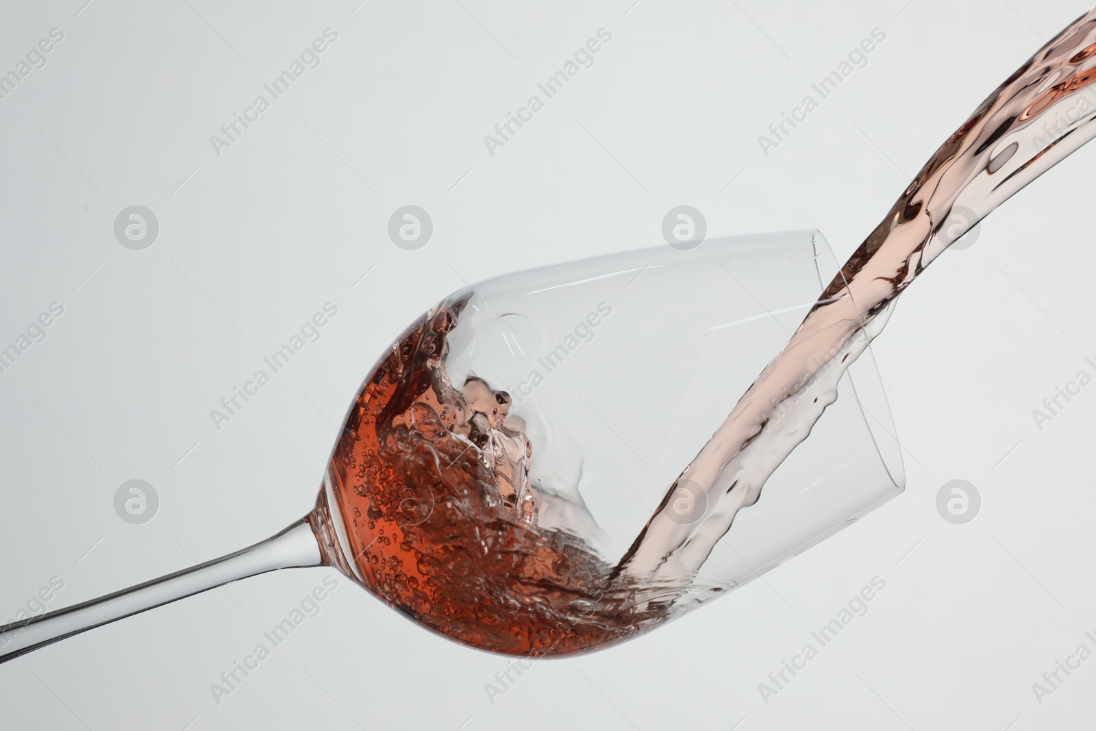 Photo of Pouring rose wine into glass on white background