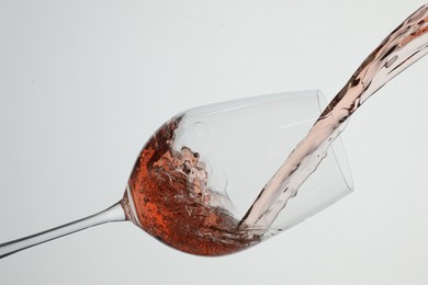 Photo of Pouring rose wine into glass on white background