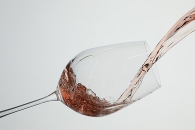 Photo of Pouring rose wine into glass on white background