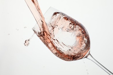 Photo of Pouring rose wine into glass on white background