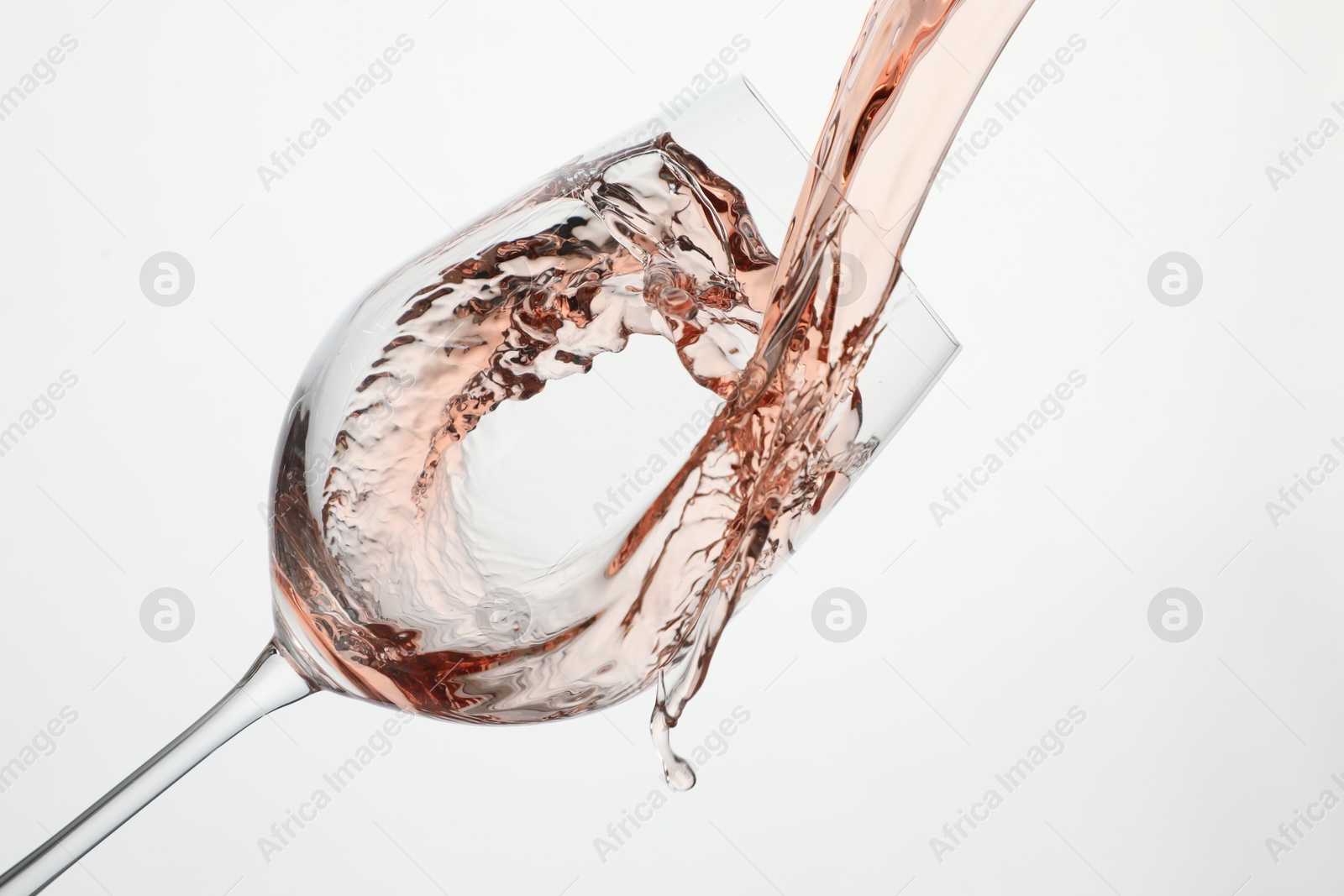 Photo of Pouring rose wine into glass on white background