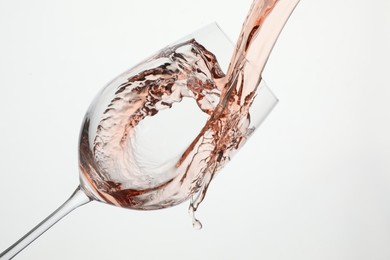 Photo of Pouring rose wine into glass on white background