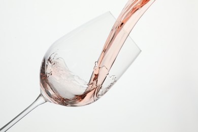 Photo of Pouring rose wine into glass on white background