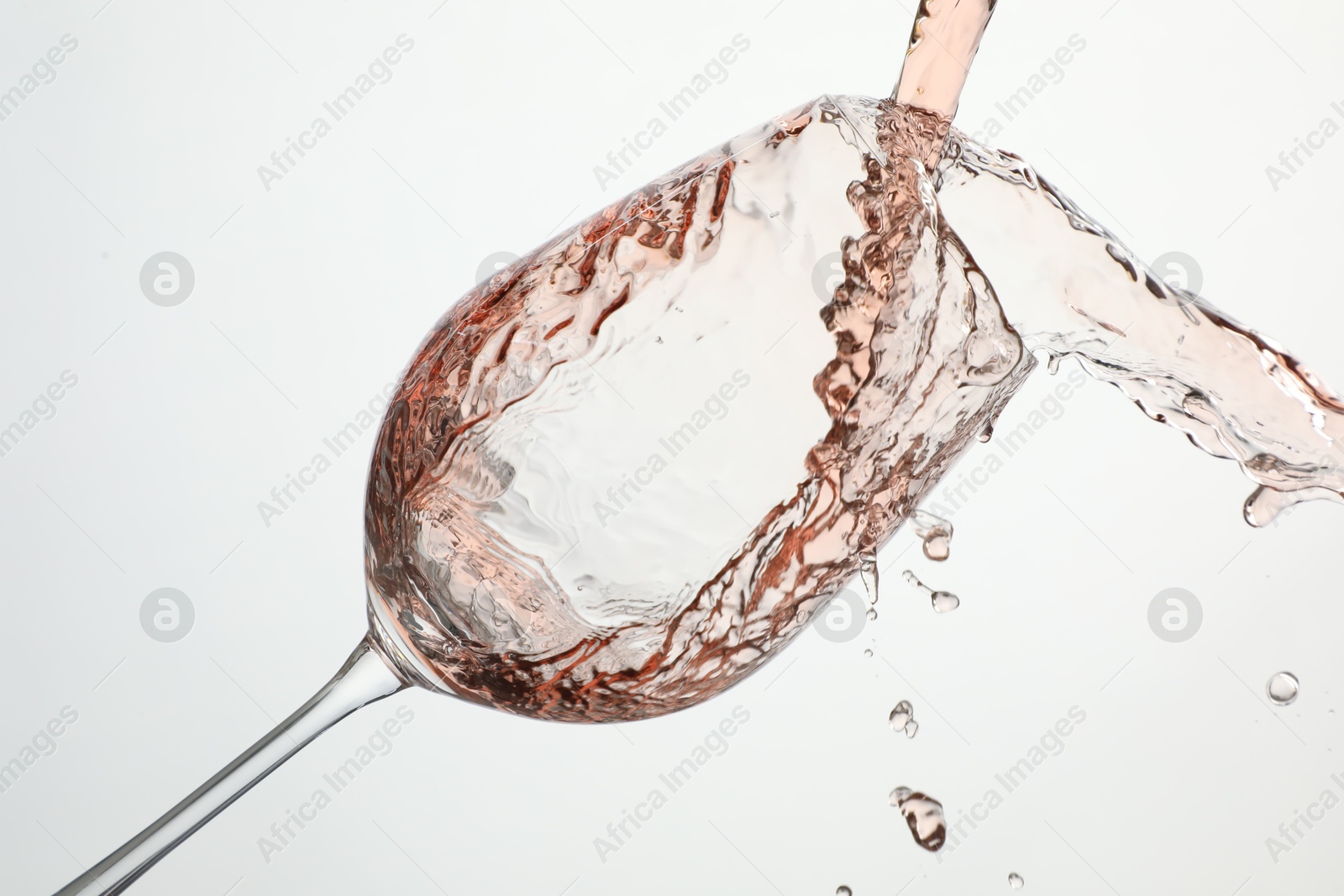 Photo of Pouring rose wine into glass on white background