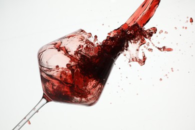 Photo of Pouring red wine into glass on white background