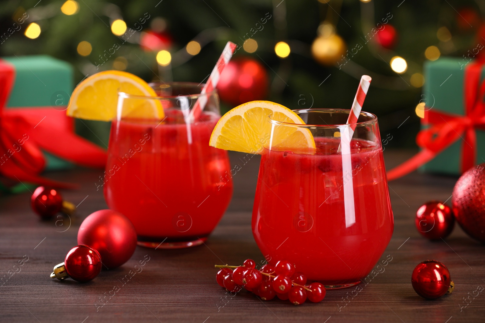 Photo of Christmas cocktail in glasses with lemon and currants on wooden table