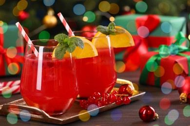 Photo of Christmas cocktail in glasses with lemon and currants on wooden table, closeup