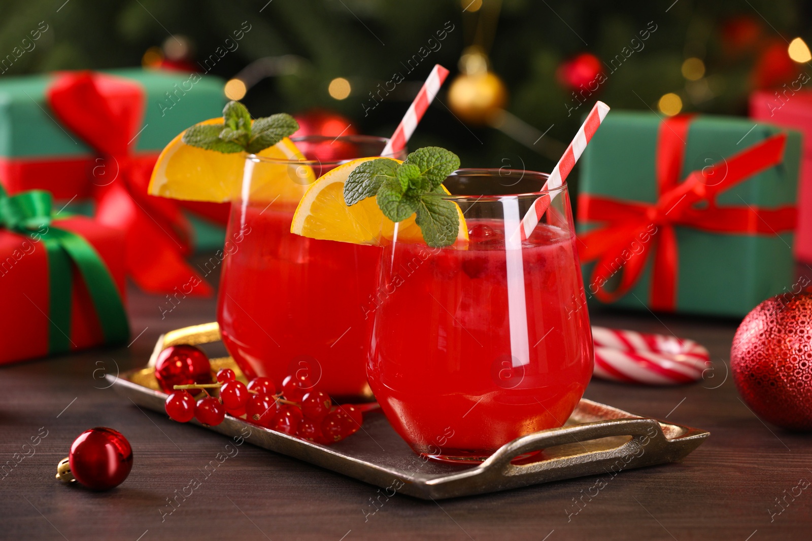 Photo of Christmas cocktail in glasses with lemon and currants on wooden table