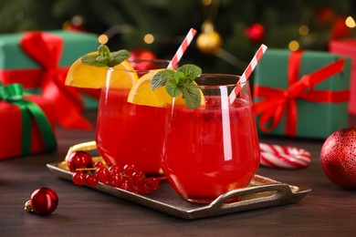 Photo of Christmas cocktail in glasses with lemon and currants on wooden table