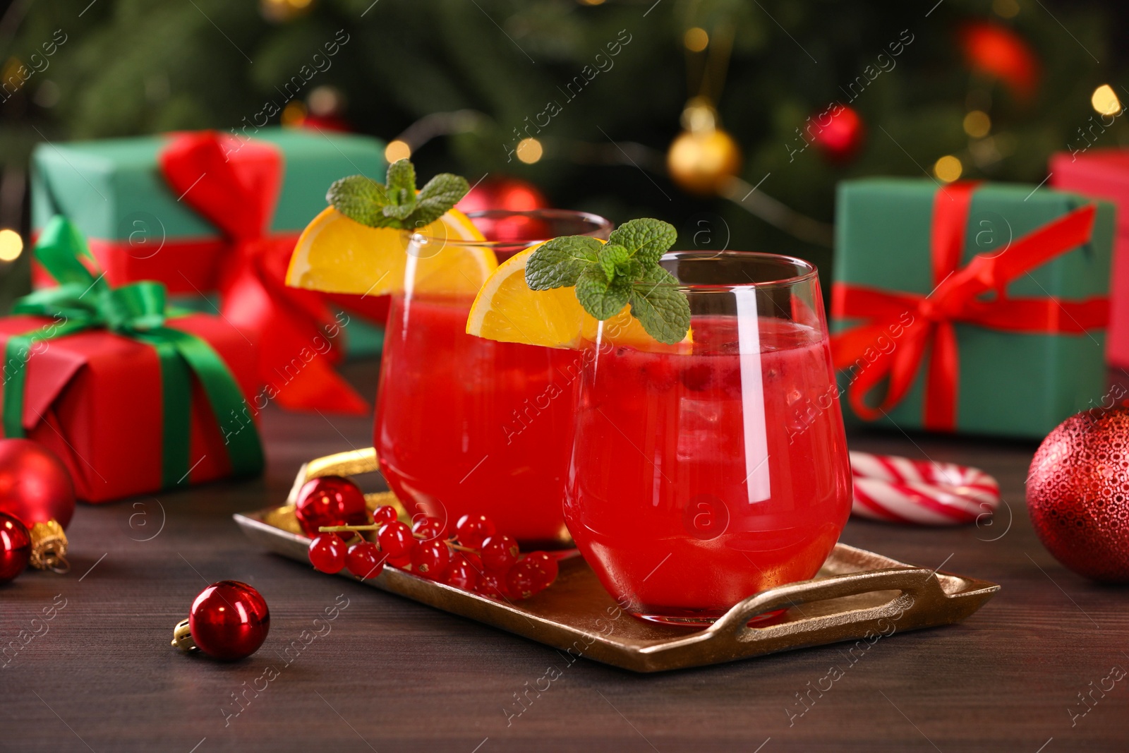 Photo of Christmas cocktail in glasses with lemon and currants on wooden table