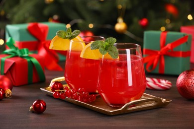 Photo of Christmas cocktail in glasses with lemon and currants on wooden table