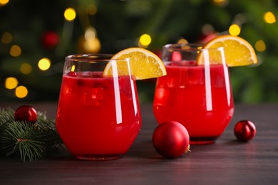 Photo of Christmas cocktail in glasses with lemon and decor on wooden table, closeup