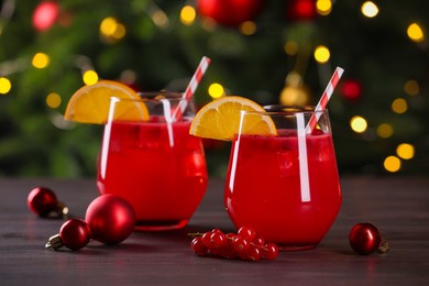 Photo of Christmas cocktail in glasses with lemon and currants on wooden table, closeup