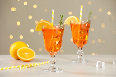 Photo of Tasty Christmas cocktail in glasses on white wooden table against blurred lights