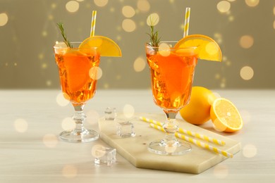 Photo of Tasty Christmas cocktail in glasses on white wooden table against blurred lights