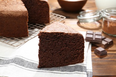 Photo of Piece of tasty chocolate sponge cake on wooden table, closeup