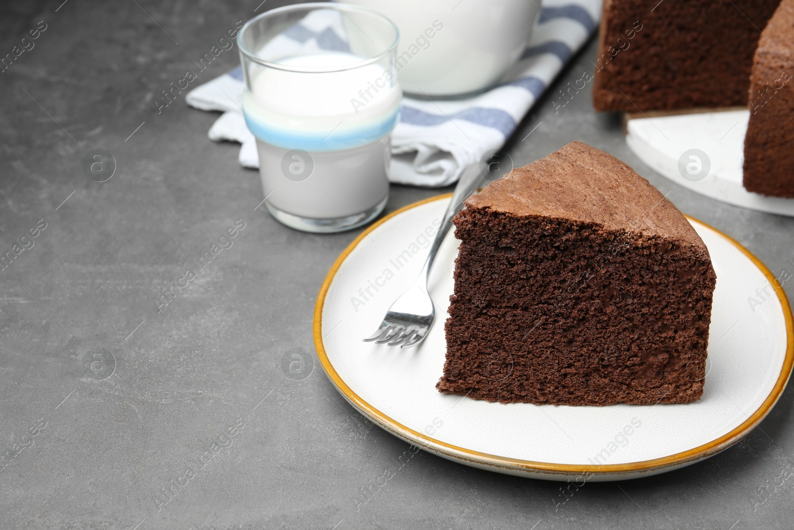 Photo of Piece of tasty chocolate sponge cake served on grey table. Space for text