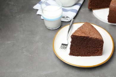 Photo of Piece of tasty chocolate sponge cake served on grey table. Space for text