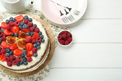 Photo of Delicious chocolate sponge cake with berries served on white wooden table, top view. Space for text