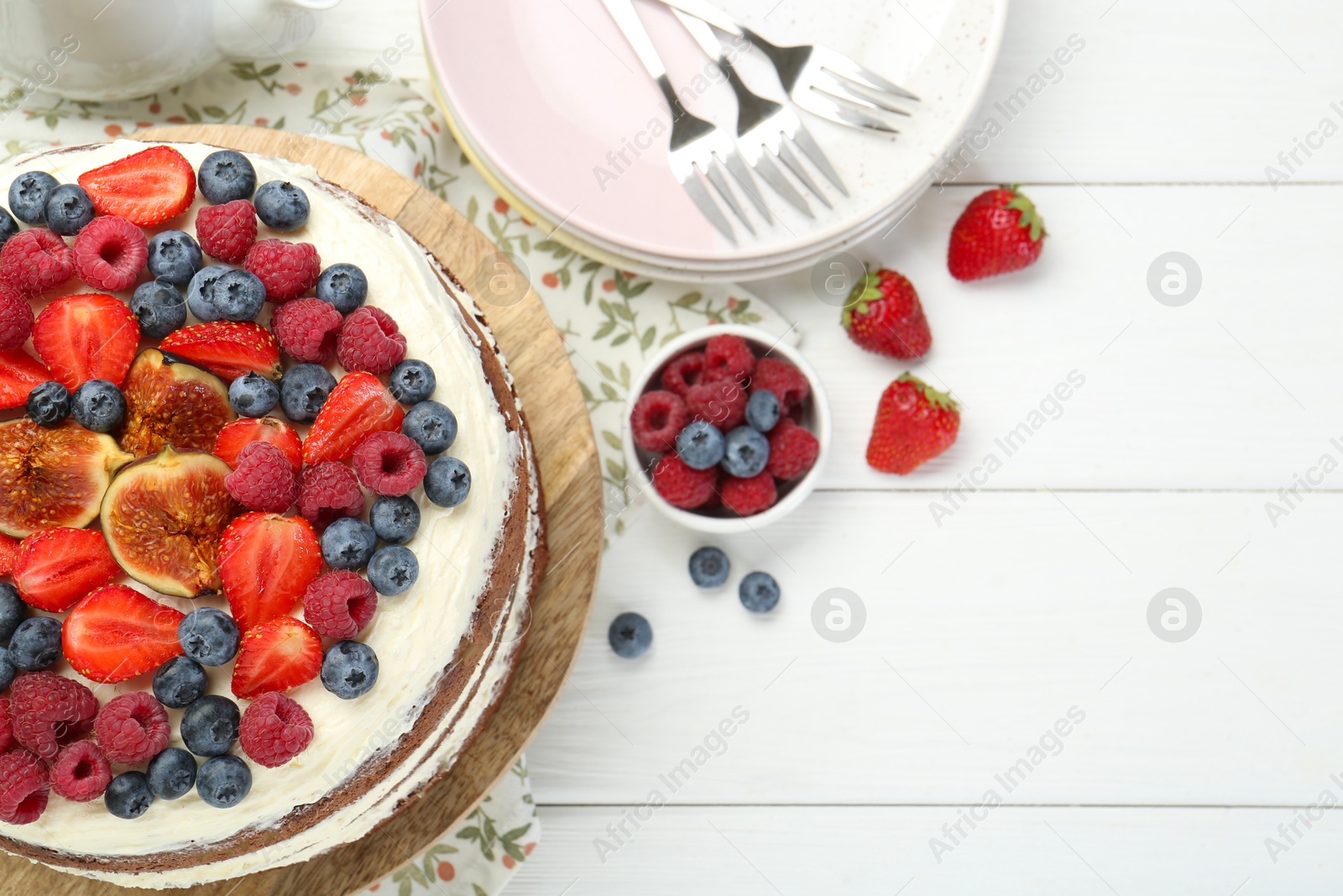 Photo of Delicious chocolate sponge cake with berries served on white wooden table, top view. Space for text