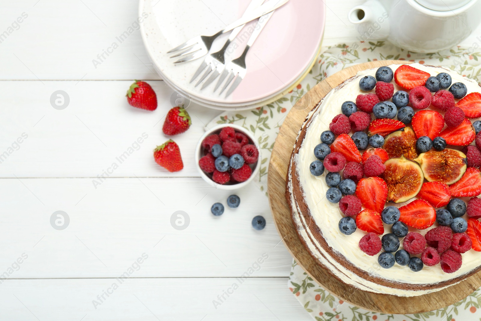 Photo of Delicious chocolate sponge cake with berries served on white wooden table, top view. Space for text