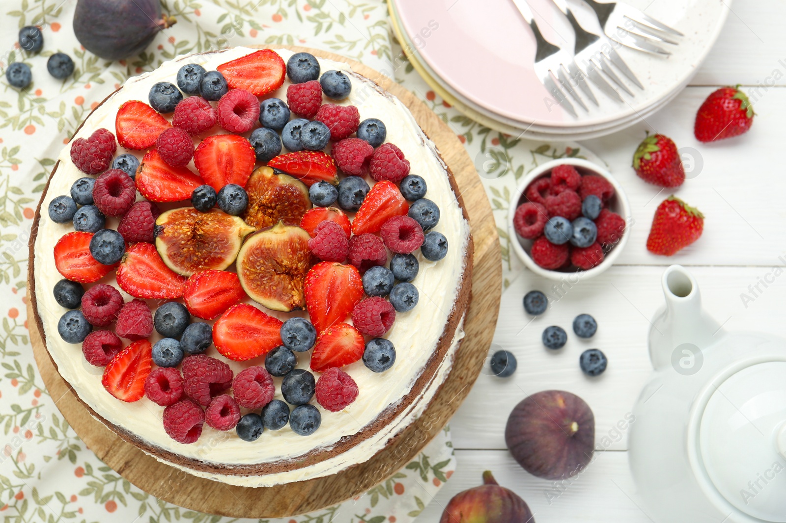 Photo of Delicious chocolate sponge cake with berries served on white wooden table, top view